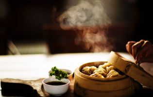 Chinese Dumplings in a Round Container Next to a Bowl of Soy Sauce